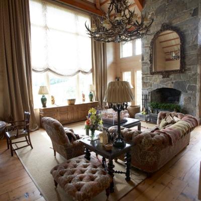Cozy living room with high wooden beams, stone fireplace, and vintage furnishings.
