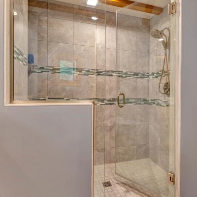 Modern shower with glass enclosure and tiled walls, featuring a decorative strip.