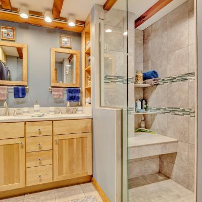 Modern bathroom with double sinks, mirrors, and a glass shower. Neutral tones and towels included.