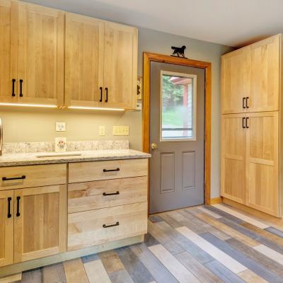 Wooden cabinets, a coffee maker, and a door with a window in a modern kitchen.