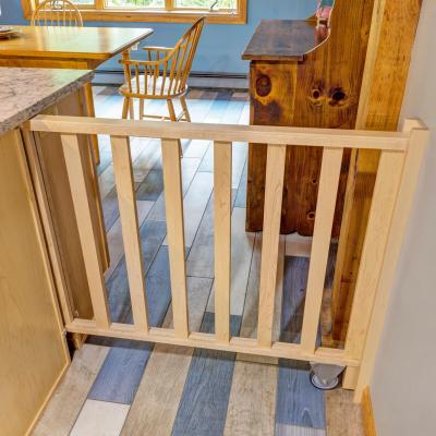 Wooden gate separating kitchen and dining area with tiled flooring.