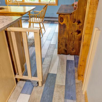 A wooden kitchen area with a gate and patterned flooring.