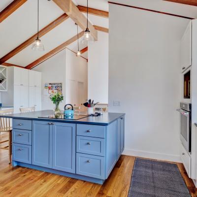 Bright, modern kitchen with a blue island, wooden beams, and stylish decor.