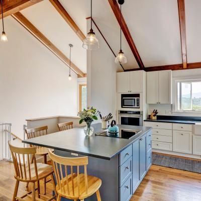 Modern kitchen with wooden beams, island, and large windows showcasing a scenic view.