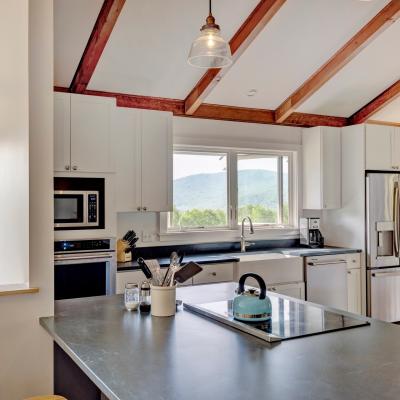 Modern kitchen with a view of mountains, featuring stainless steel appliances and a blue kettle.