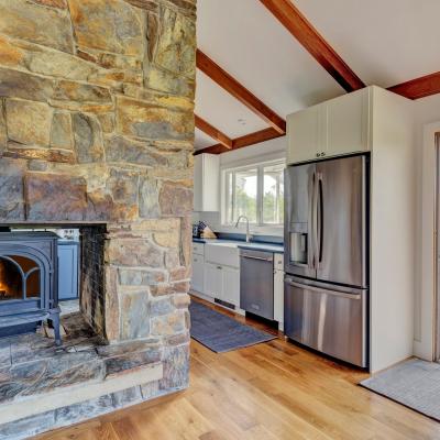 Cozy kitchen with stone fireplace, modern appliances, and a view of the outdoors.