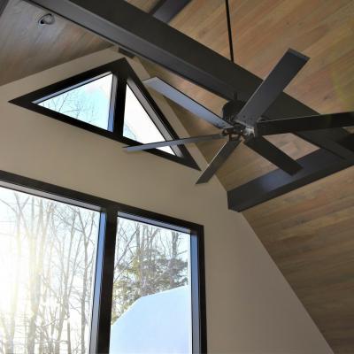Modern interior with triangular windows and a ceiling fan, featuring wood accents.