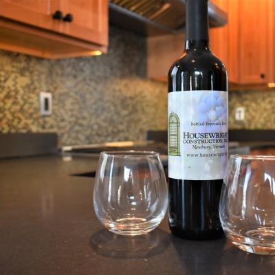 Wine bottle with label beside two empty glasses on a kitchen counter.