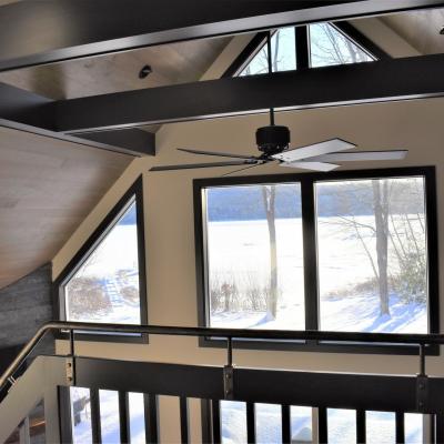 View from an interior stairwell featuring a ceiling fan and large windows overlooking snowy scenery.