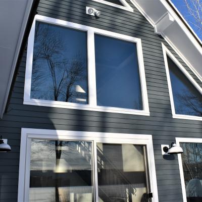 Modern house exterior showing large windows and dark siding with a clear sky.
