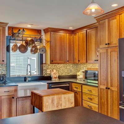 Modern kitchen with wood cabinets, black countertops, and hanging pots.