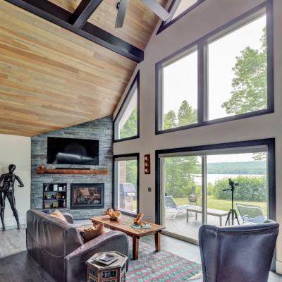 Modern living room with tall windows, fireplace, and scenic lake view.