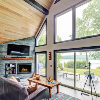 Stylish living room with large windows, fireplace, and view of a lake.
