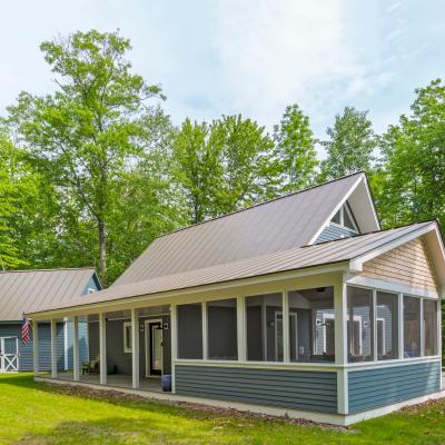 A modern house with a screened porch surrounded by lush green trees.
