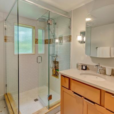 Modern bathroom featuring a glass shower, light tile, and an orange vanity.