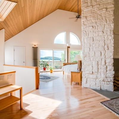 Bright, modern interior with wooden accents, a stone fireplace, and views of nature.