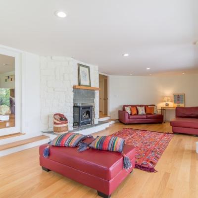 Modern living room with red furniture, a stone fireplace, and colorful rugs.