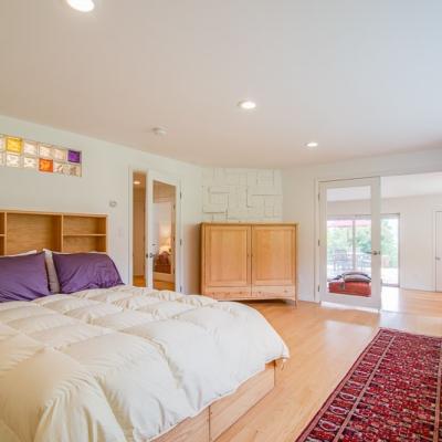 Bright bedroom with a large bed, wooden furniture, and glass block window accents.