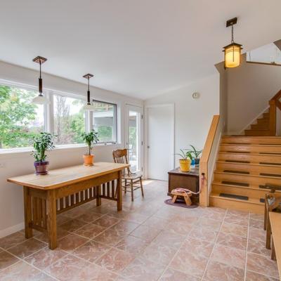 Bright entryway with a wooden table, chairs, plants, and a staircase.