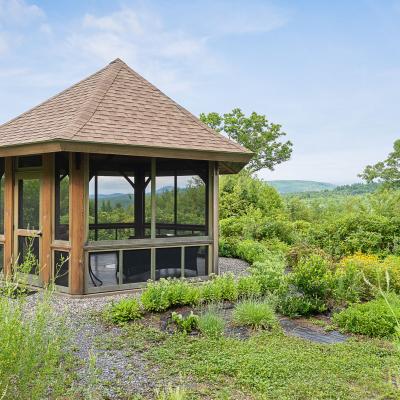 A wooden gazebo surrounded by lush greenery and colorful flowers.