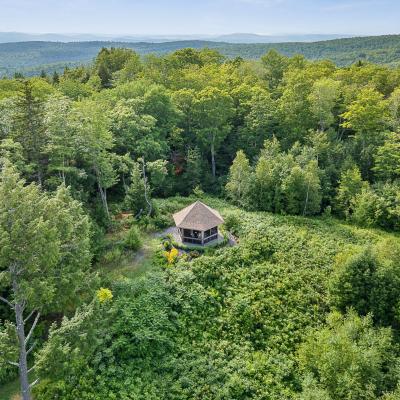 Aerial view of a rustic cabin surrounded by lush greenery and mountains in the distance.