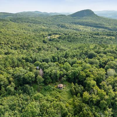 Aerial view of lush, green forested hills and a small structure nestled in the trees.