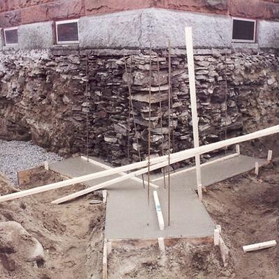 Excavated foundation site with concrete slab and wooden supports.