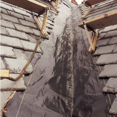 Roof under construction, featuring slate tiles and black underlayment at the peak.
