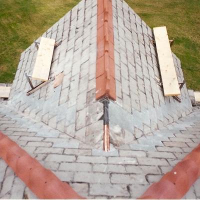 Aerial view of a roof under construction with wooden scaffolding and a lawn mower below.