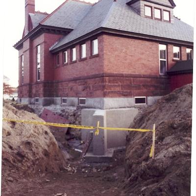 Historic brick house with construction site and caution tape in foreground.