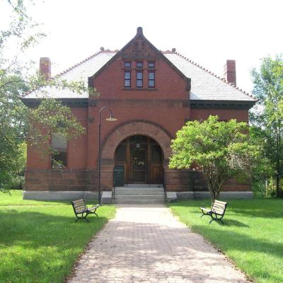 Historic brick library building surrounded by lush greenery and benches.
