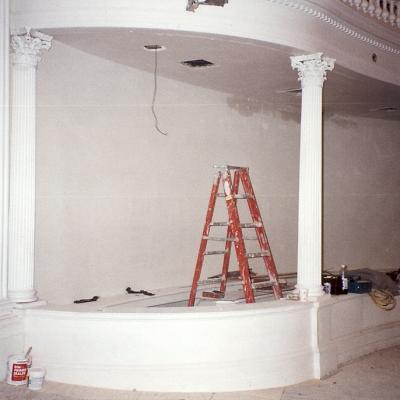 A partially finished room with columns, a ladder, and construction materials.