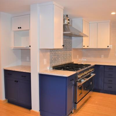 Modern kitchen featuring blue cabinetry, marble countertops, and a large gas range.