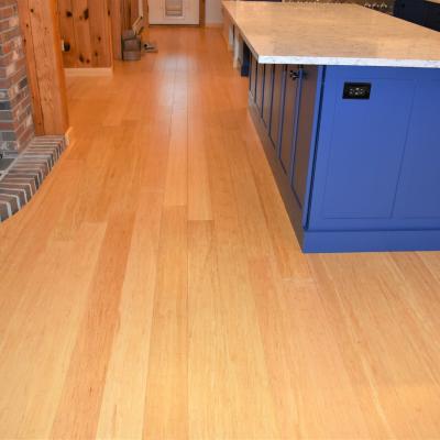 A modern kitchen with bamboo flooring and a blue island.