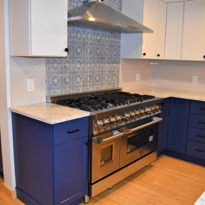Modern kitchen with blue cabinets, stainless steel range, and decorative tile backsplash.