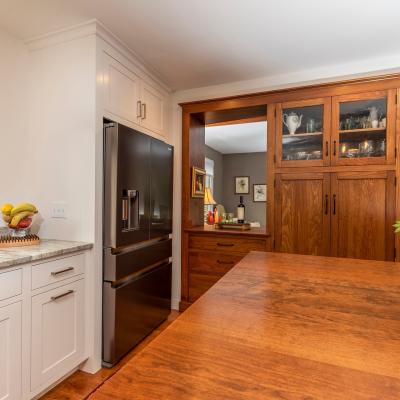Modern kitchen with dark fridge, wooden cabinets, and a fruit bowl on the counter.