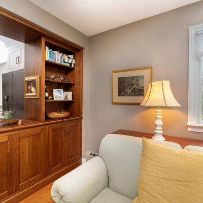 Stylish living space with a wooden shelf, books, and a cozy sofa near a window.
