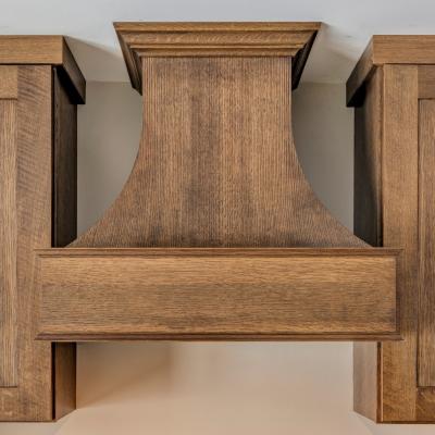Wooden kitchen range hood flanked by matching cabinets. Modern and sleek design.
