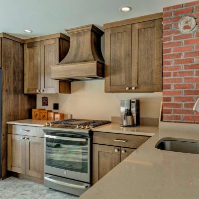 Modern kitchen with dark wood cabinets, stainless steel appliances, and a brick accent wall.