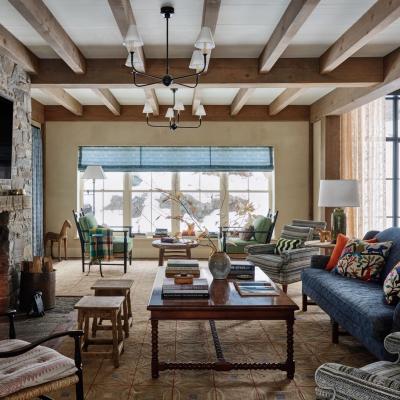 Cozy living room with a stone fireplace, colorful furnishings, and large windows.