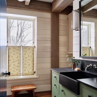 Relaxing bathroom with green cabinetry, natural wood accents, and patterned window shades.