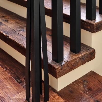 Black railing supports next to wooden stairs with rustic texture.