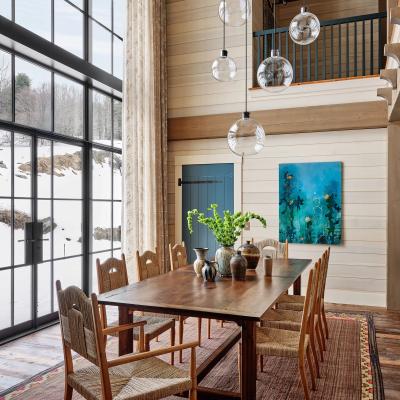 Modern dining room featuring a wooden table, woven chairs, and large windows.