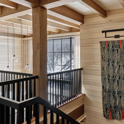 Modern interior with wooden beams, black railings, and a patterned wall hanging.