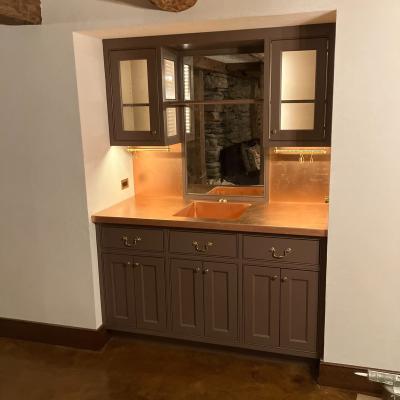 Modern kitchen with dark cabinets and a copper countertop featuring a sink.