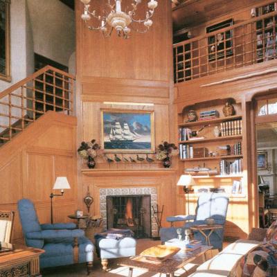 Cozy wood-paneled living room with blue chairs, a fireplace, and a chandelier.