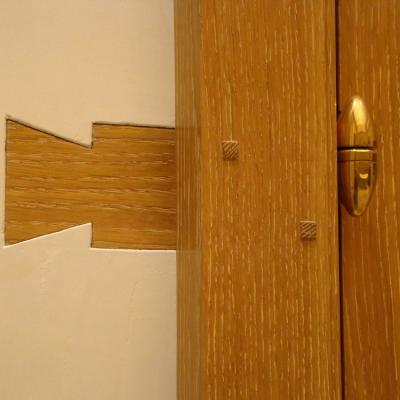 Close-up of a wooden door showing a fitted keyhole and hinge detail.