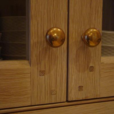 Close-up of wooden cabinet doors with brass knobs and decorative square inlays.