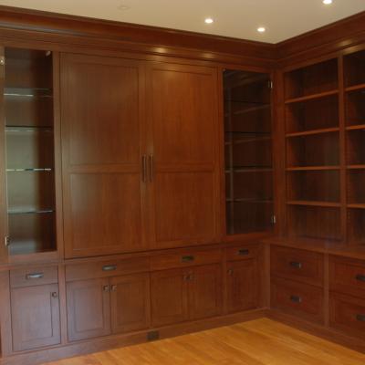 Wooden shelving unit with cabinets and drawers, empty and well-lit.