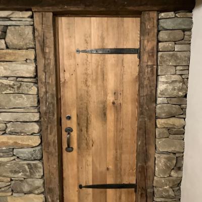Wooden door framed by rustic stone wall with metal accents.